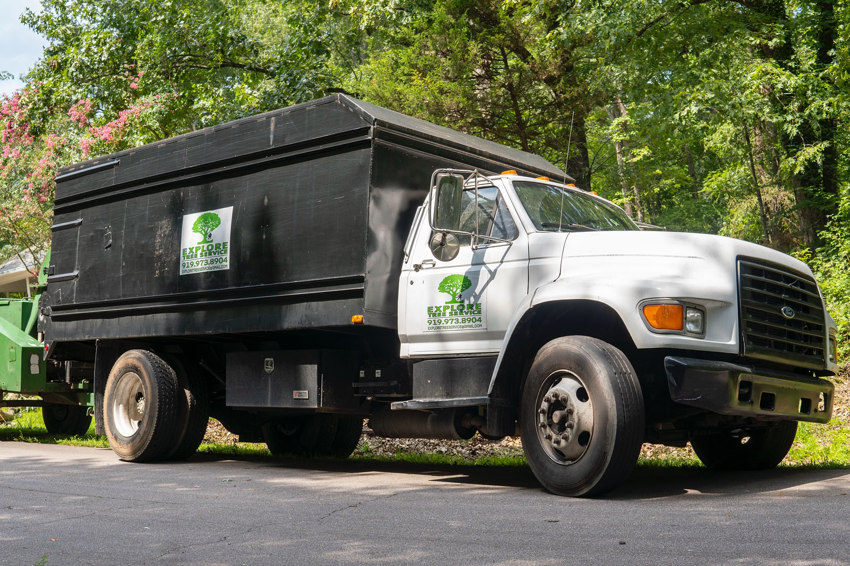 A branded tree service truck with a wood chipper, ready for work by Explore Tree Service in Durham, NC.