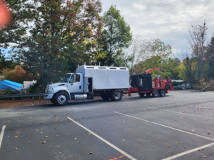 A white tree service truck with a large wood chipper attached, ready for work by Tommy Lowery's tree service in Raleigh, NC.