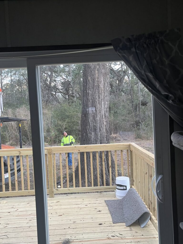 A tree service worker in a high-visibility vest operating a chainsaw near a large tree, performing work for Ayla Tree Service in Bloomingdale, GA.