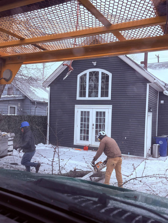 A tree service worker cutting logs with a chainsaw during a job by Robert Tree Service LLC in Cleveland, OH.