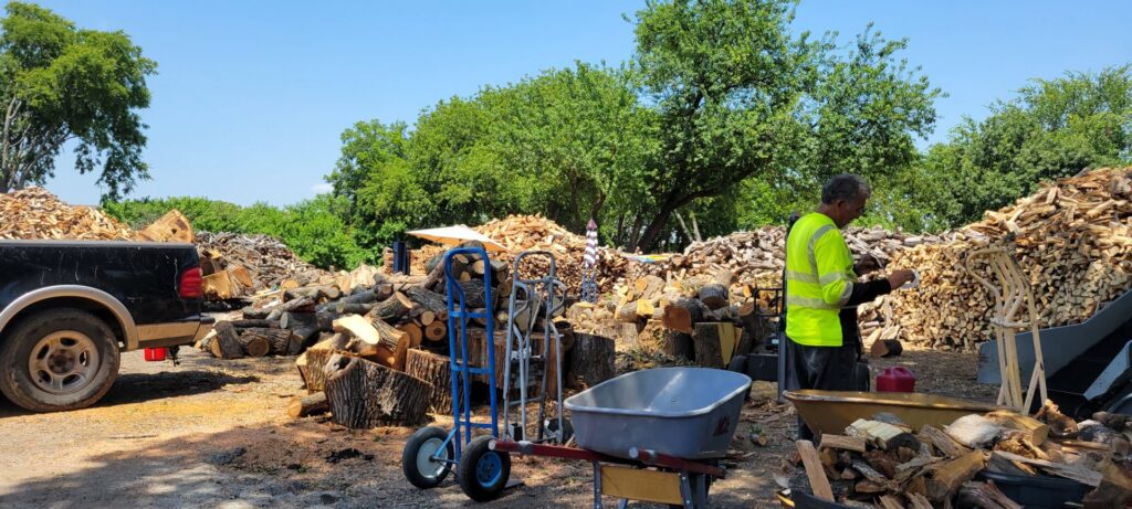 A tree service worker in a high-visibility vest processing firewood at Personal Touch Tree Service in Dallas, TX