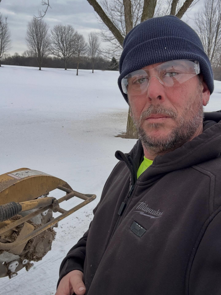 A tree service worker operating a stump grinder in a snowy field for Jason's Tree Service Llc. in Garden City, MI.