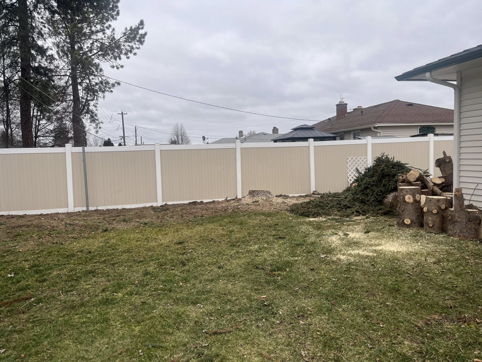 A tree stump and pile of debris in a backyard after tree removal by Catchpole Tree Service in Spokane, WA