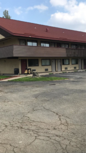 A tree stump in a commercial parking lot, showing a completed tree removal service by K.M.C Lawn & Tree service in Peoria, IL.