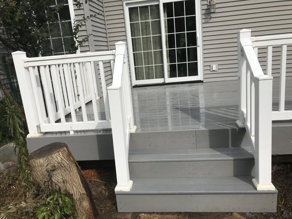 A freshly cut tree stump next to a new deck, showing tree removal services by Green Way Landscaping LLC in Iowa City, IA.