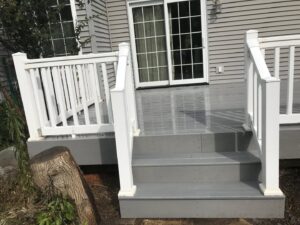 A freshly cut tree stump next to a new deck, showing tree removal services by Green Way Landscaping LLC in Iowa City, IA.