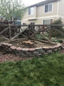 A tree stump that has been removed from a garden bed, demonstrating stump grinding by AAA Emergency Tree Service LLC in Denver, CO.