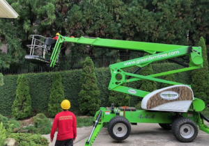 A Green Fern Tree Service worker operating a boom lift for tree trimming in Roswell, GA.