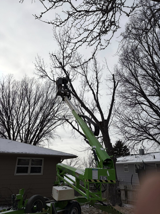 A professional using a bucket lift for tree trimming services by Falcon Enterprises LLC in Pierre, SD