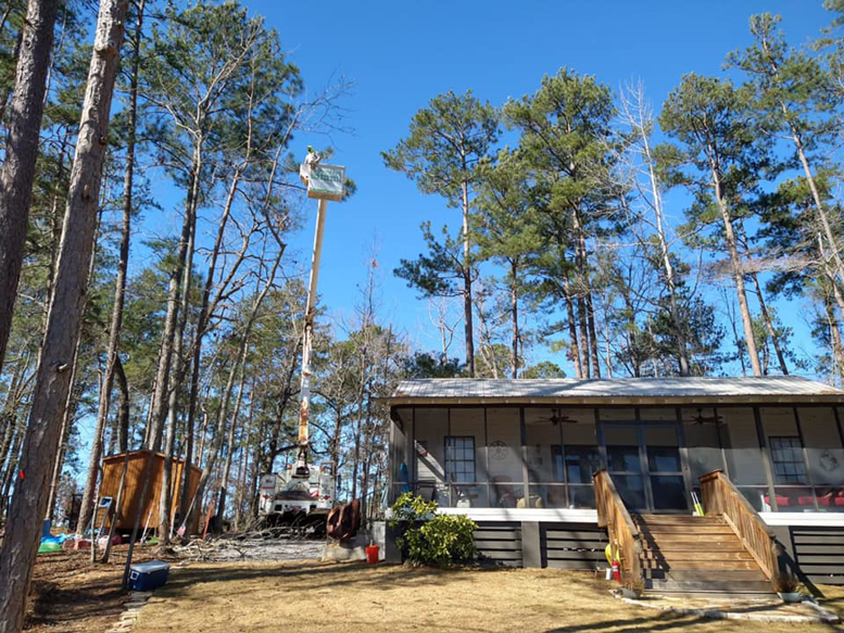 A worker in a bucket truck performing tree trimming services for Emerald Tree Services in Alabaster, AL