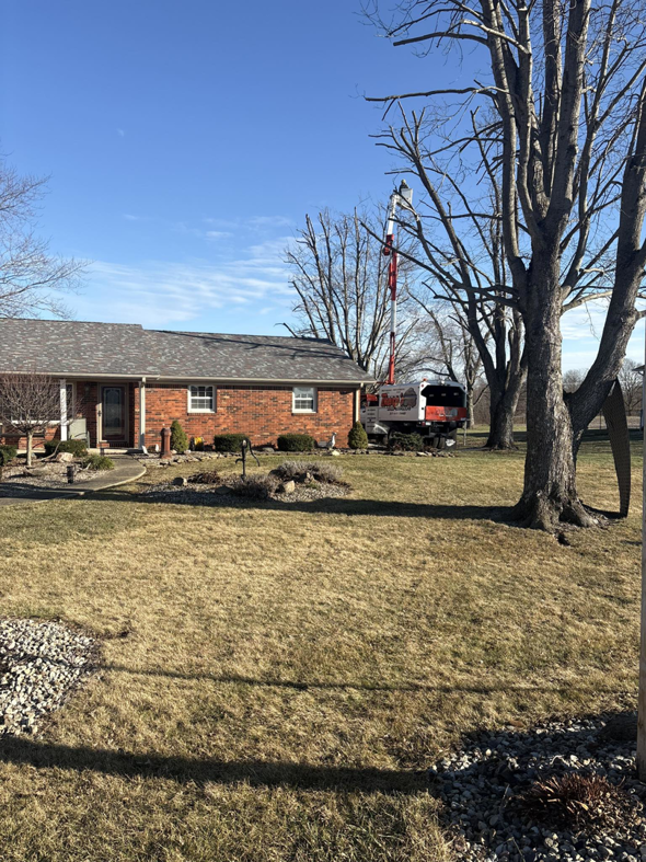 A bucket truck used for tree trimming or removal near a residential home by Tharp's Lawn Care & Tree Service in Indianapolis, IN