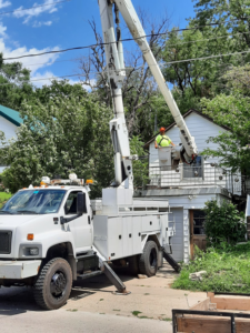 A worker in a bucket truck preparing for tree trimming near a house by Javier Medina Tree Service LLC in DrDenison, IA.