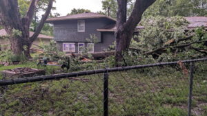 A bucket truck performing tree trimming services near a residential house by Top Notch Tree Care in Holt, MI.