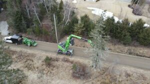 A green Sennebogen machine performing tree trimming and removal services for Dark Arbor Tree Care in Portland, ME.