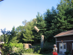A crane lifts a large tree trunk section from a tall stump during a tree removal service by Mark's Tree & Stump Removal in Roanoke, VA.