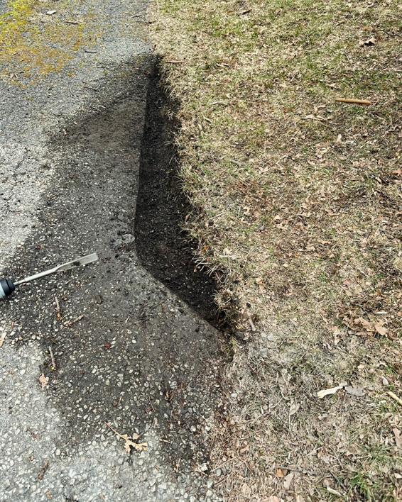 A trench being dug along the edge of a driveway, a service provided by Blackcap Handyman in Portland, ME.