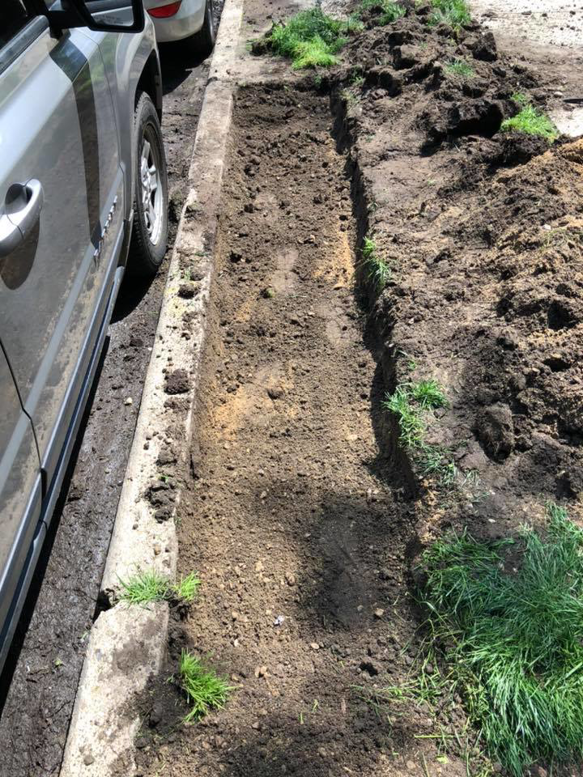 A trench dug alongside a curb, ready for drainage or utility installation by Pro Home Solutions in Aiken, SC.
