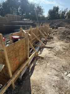 Trenching and pipe laying next to wooden formwork at a construction site by Stealth Civil Contracting in Austin, TX.