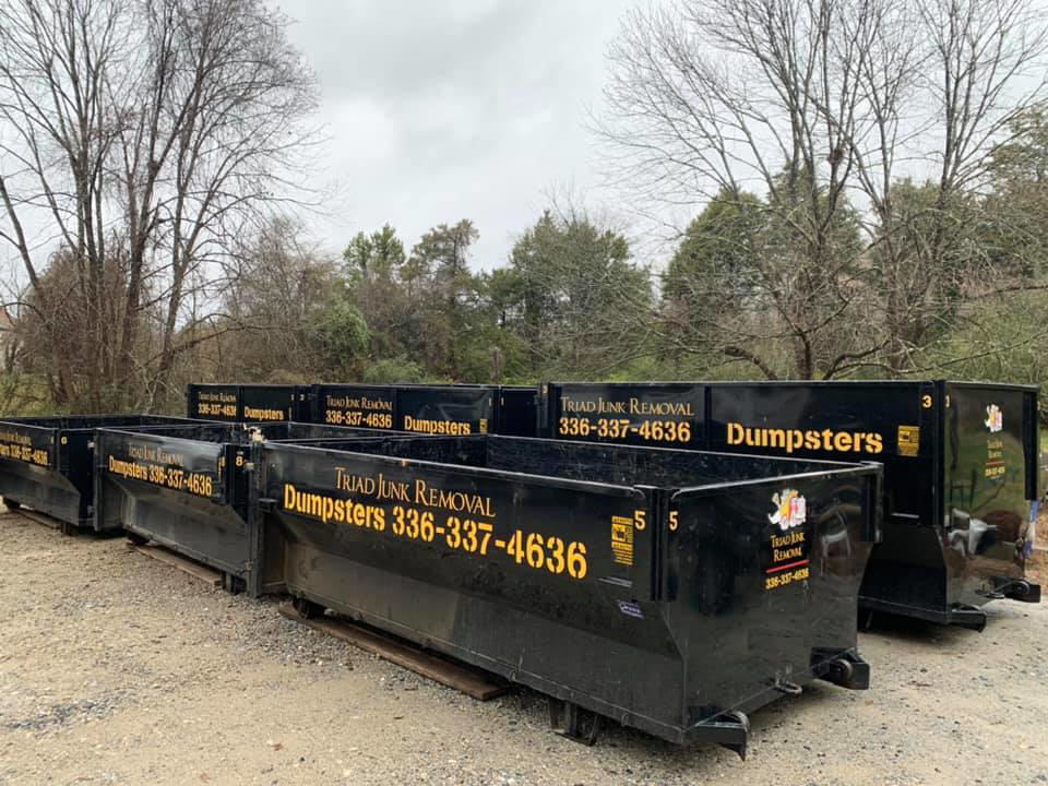Multiple Triad Junk Removal roll-off dumpsters ready for use at job sites in Greensboro, NC.