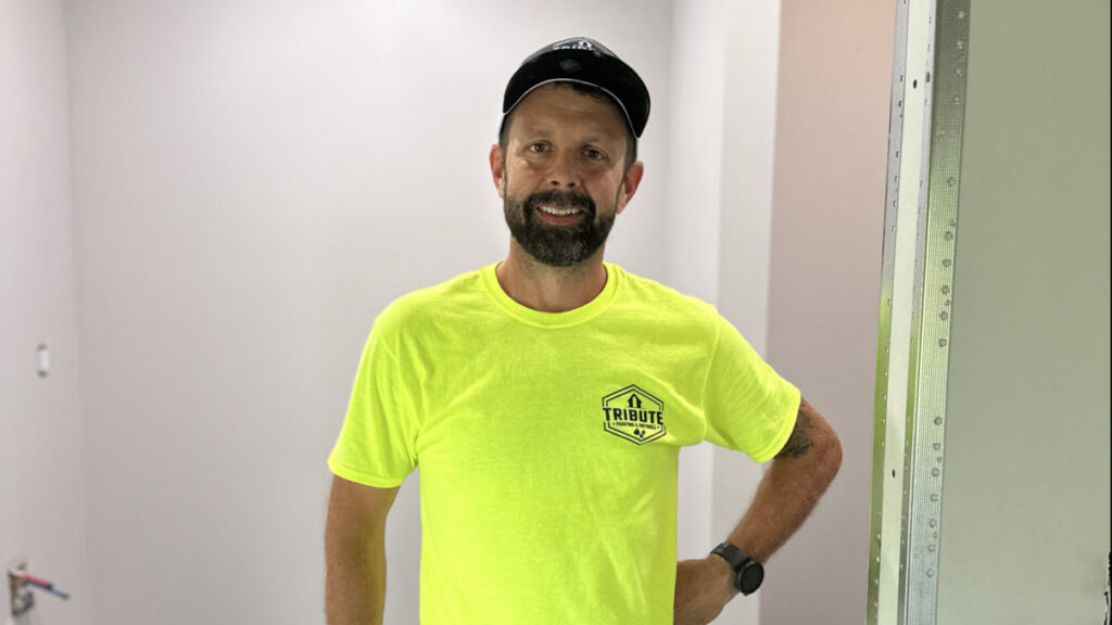 A friendly worker from Tribute Painting & Drywall standing in a newly painted room in St. Louis, MO.
