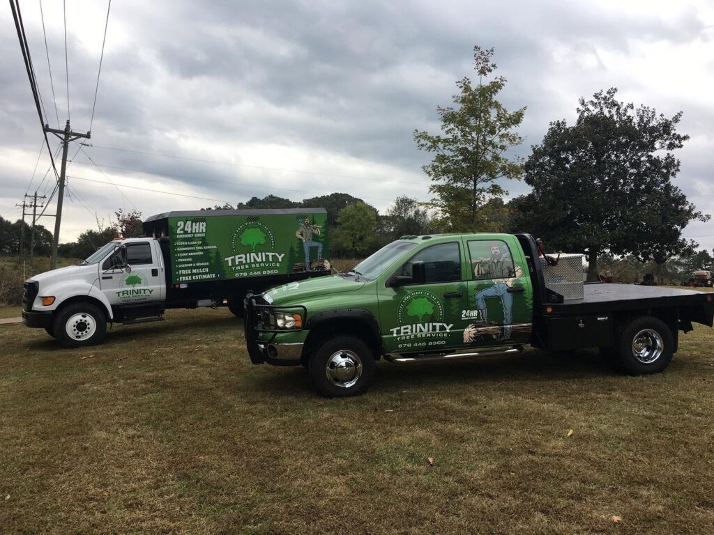 Two branded Trinity Tree Service trucks, including a chipper truck and a flatbed, ready for work in Cumming, GA.