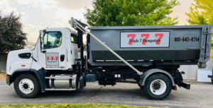 A Triple 7 Dumpsters roll-off truck with a gray dumpster ready for junk removal services in Ogden, UT.