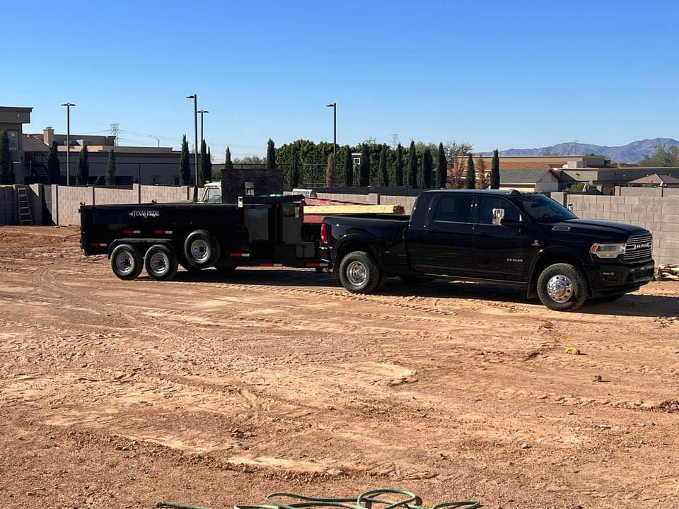 A heavy-duty truck with a large dump trailer parked on a job site for Sunrise Mountain Hauling LLC in Peoria, AZ.