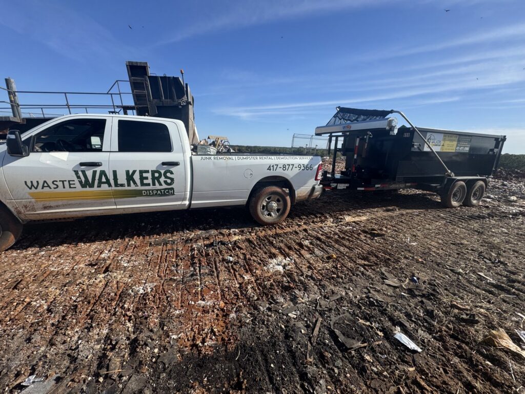 A Waste Walkers Dispatch truck and dump trailer at a landfill for junk disposal in Springfield, MO.