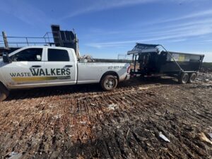 A Waste Walkers Dispatch truck and dump trailer at a landfill for junk disposal in Springfield, MO.