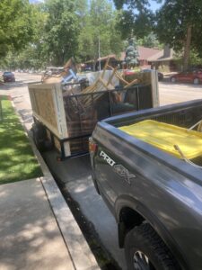 A truck and trailer full of furniture and various items being hauled by Trash It All Hauling And Junk Removal LLC in Fort Collins, CO.