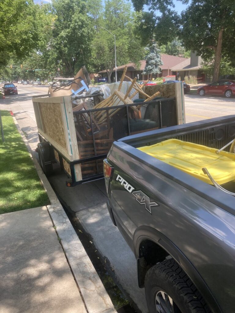 A truck and trailer full of furniture and various items being hauled by Trash It All Hauling And Junk Removal LLC in Fort Collins, CO.