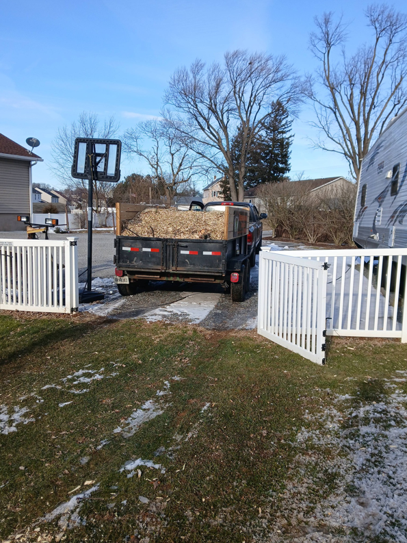 A truck pulling a trailer loaded with wood chips and debris from a tree service job by RJ Robinson Family Tree Service LLC in York, PA