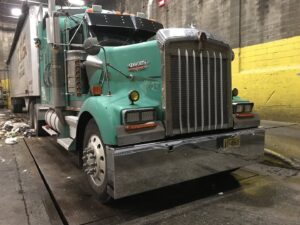 A Voyager Trucking semi-truck at a waste transfer station or processing facility in Newark, NJ