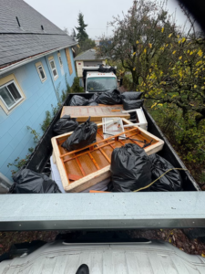 Overhead view of an All City Junk Removal truck bed filled with black trash bags, wooden frames, and debris from a cleanup job in Kent, WA.