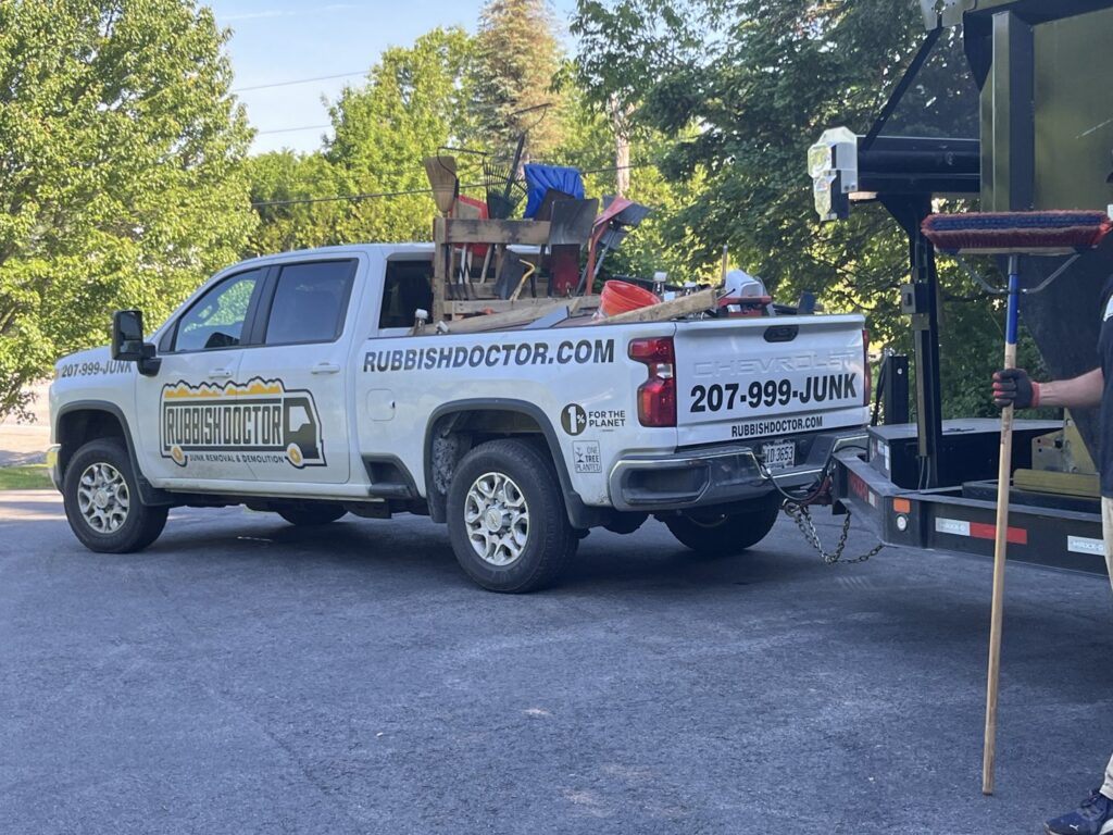 A Rubbish Doctor branded pickup truck with its bed filled with various junk items in Portland, ME.