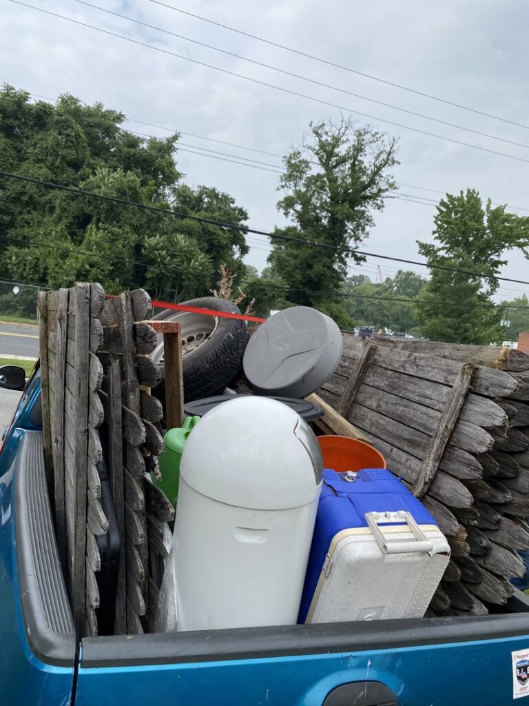 A truck bed loaded with old fence panels, tires, and other miscellaneous junk for removal by Navarro Demo LLC in Rockville, MD