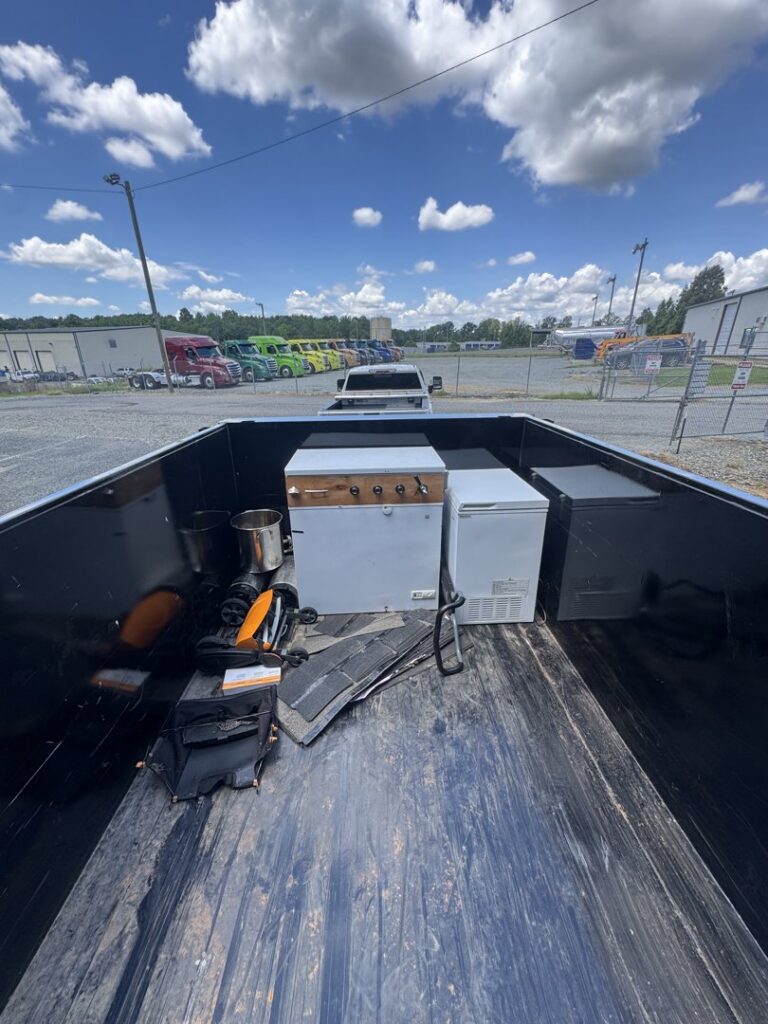 The bed of a Junkjet pickup truck loaded with old appliances and other items for removal in Charlotte, NC.