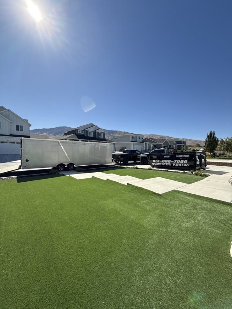 A truck delivering an empty dumpster on a trailer for Utah Valley Dumpsters in Provo, UT.