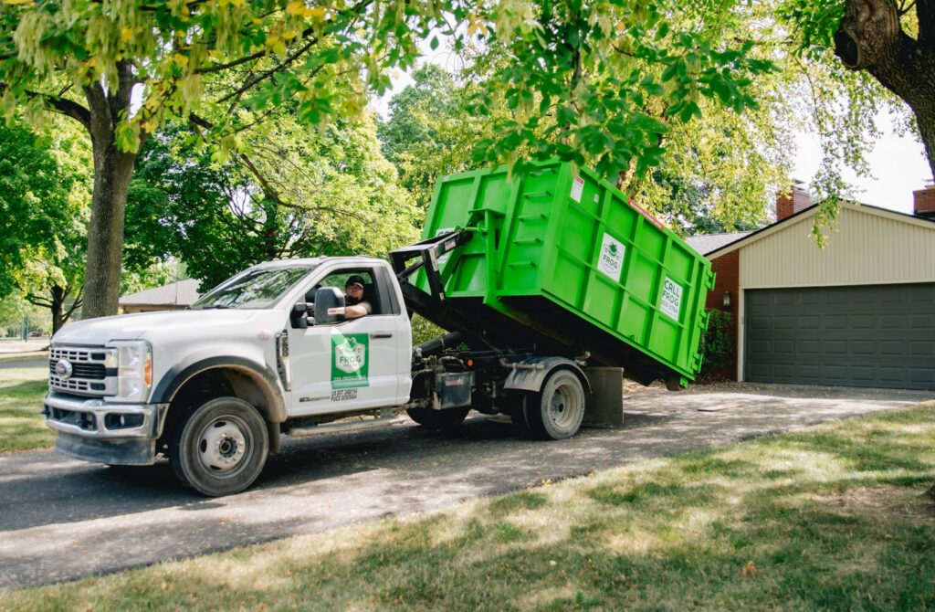 A Frog Hauling truck delivering a green dumpster to a residential property in Columbus, OH.