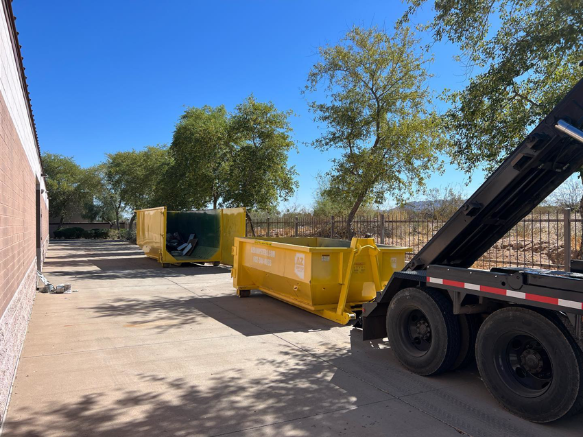 A truck delivering two yellow dumpsters for junk removal services by AZ Dumpster Rentals in Surprise, AZ