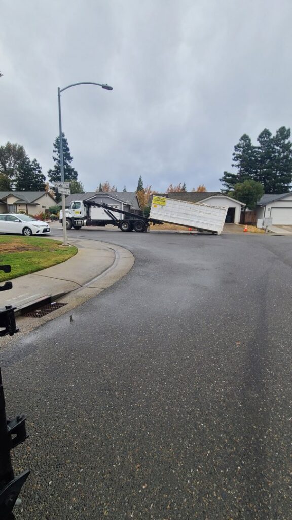 A Waste Removal and Recycling, Inc. truck deploying a roll-off dumpster on a residential street in Sacramento, CA.