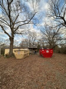 An American Dumpster Rentals truck deploying a green dumpster at a commercial site in Morrilton, AR.