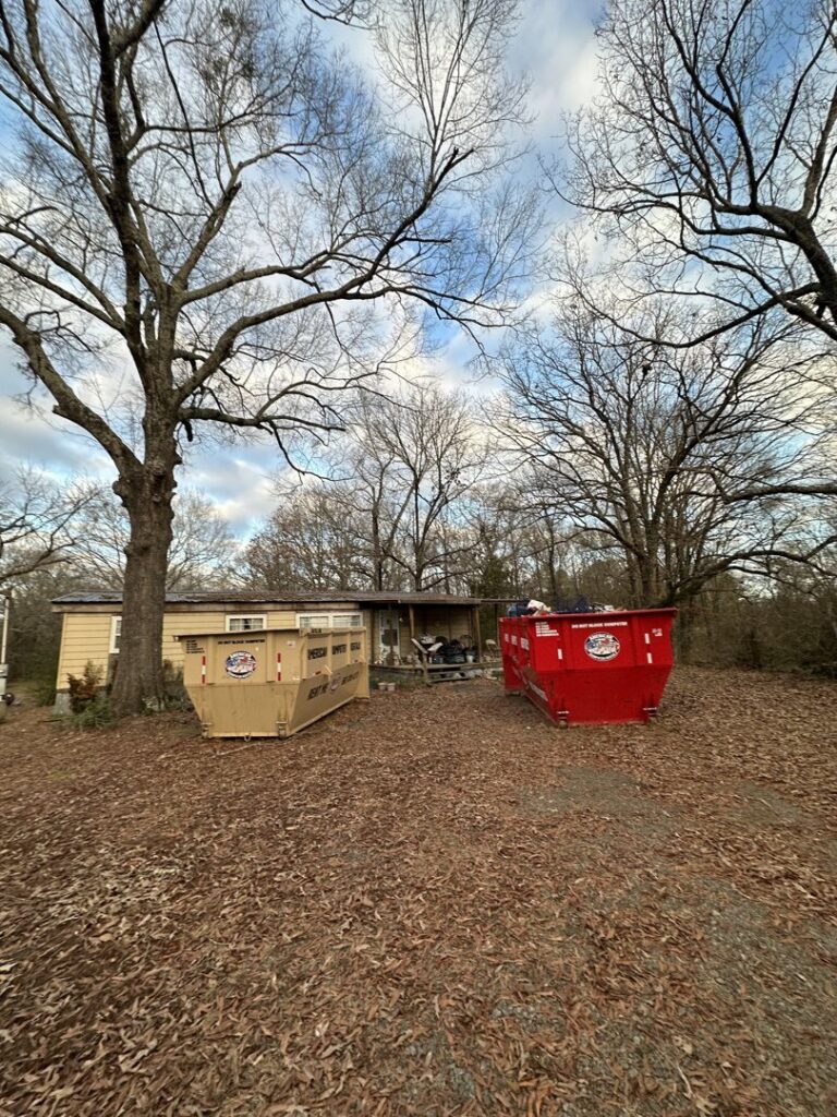 An American Dumpster Rentals truck deploying a green dumpster at a commercial site in Morrilton, AR.