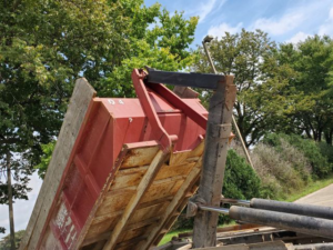 A SS ROLL OFF Dumpsters truck deploying a red roll-off dumpster for a junk removal job in Rockford, IL.