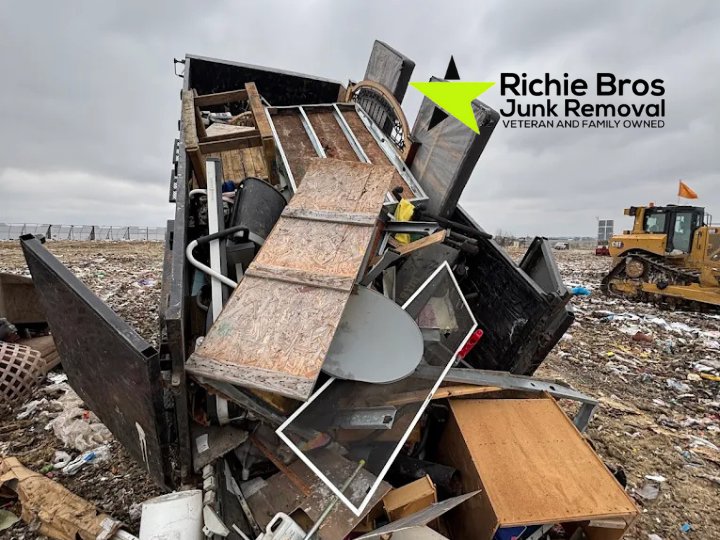 A truck's dumpster bed overflowing with various junk items at a landfill, handled by Richie Bros Junk Removal in Urbandale, IA.