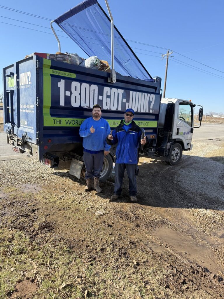 Two 1-800-GOT-JUNK? crew members standing in front of their truck filled with junk in Bronx, NY