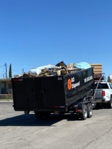 A GO Disposal Roll Off Services truck hauling a trailer filled with general junk and debris in El Paso, TX.