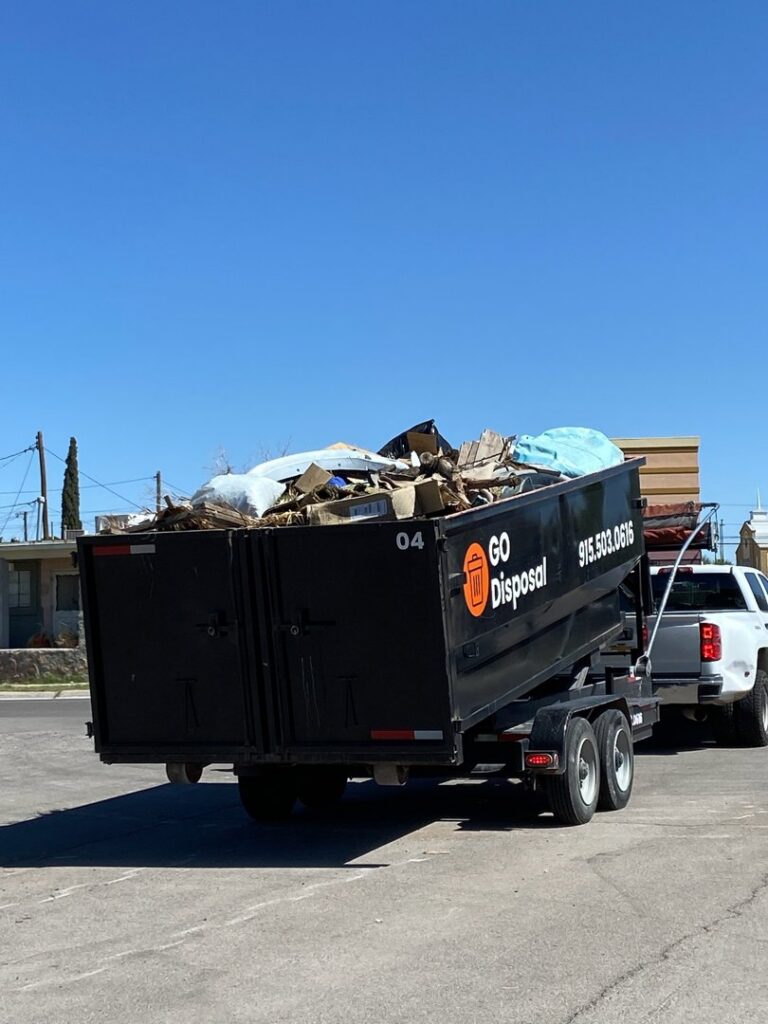 A GO Disposal Roll Off Services truck hauling a trailer filled with general junk and debris in El Paso, TX.