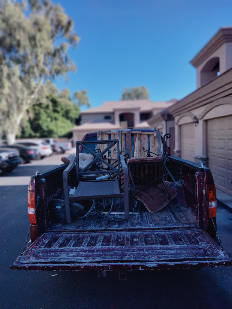 A pickup truck loaded with old patio furniture and wooden pallets for removal by Harvey's Junk Hauling and Recycling LLC in Scottsdale, AZ.