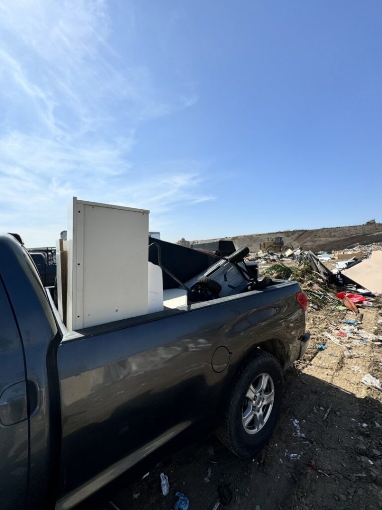 A pickup truck hauling a refrigerator and other junk to a disposal site for Johan's Junk Removal and Hauling in San Diego, CA